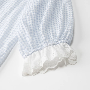 Detailed close-up of blue and white checkered baby romper sleeves with delicate lace edges