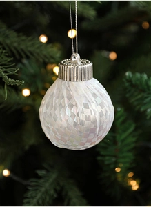 Detailed view of checkered Christmas tree ornament with pearlescent finish on pine branch