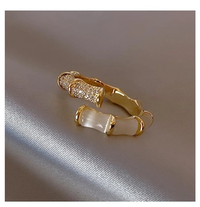 Macro detail of gold bamboo ring featuring sparkling zircons and white cat eye stones