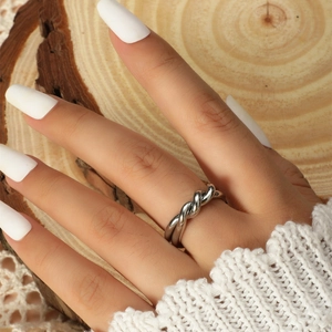 Detail of a silver twisted metal ring on a finger with a minimalist braided design