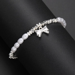 Detail of silver bow pendant and imitation pearls displayed on a black stand