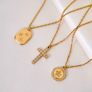 Elegant gold-plated necklaces with cross and star pendants on white silk background