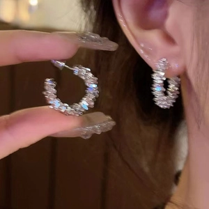 Macro shot of silver-tone hoop earrings featuring pave-set crystals and refined details