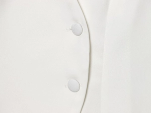 Detailed close-up of premium fabric buttons on a white tailored slim-fit luxury blazer
