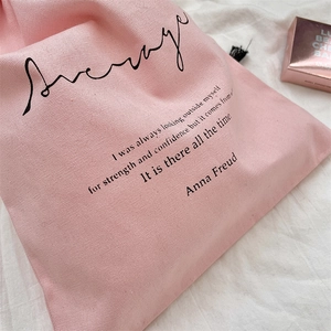 Macro shot of pink canvas drawstring bag with printed text and black cord detail