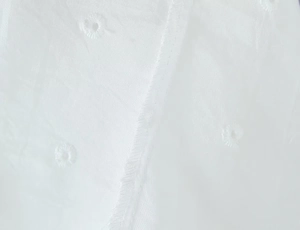 Dettaglio ravvicinato del tessuto di cotone ricamato bianco con cuciture in pizzo