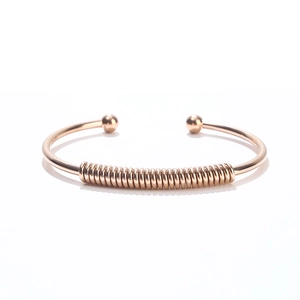 Macro detail of rose gold stainless steel open bangle with coil design and smooth ball ends