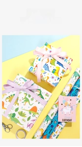Detail of cartoon dinosaur birthday wrapping paper with colorful ribbons and cards