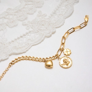 Détail du bracelet en acier inoxydable doré 18K avec médaille ange et breloques cœur