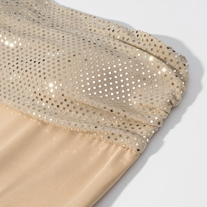 Gros plan des paillettes champagne et du tissu élastique sur une robe de soirée chic