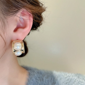 Gros plan de boucles d'oreilles vintage dorées en C avec perles blanches sur un mannequin