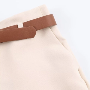 Detail of beige trousers with rolled hem featuring a brown faux leather belt