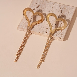 Detail of gold heart earrings with long crystal tassel fringe on a natural stone base