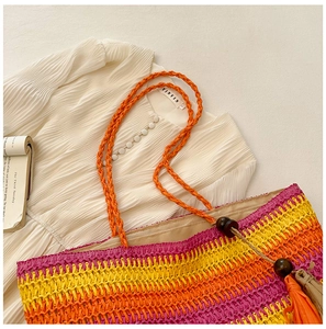 Close-up of rainbow striped straw tote bag with beaded fringe and white pleated top