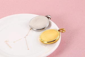 Close-up of oval gold and silver stainless steel heart pendants on a ceramic dish