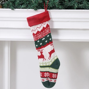 Knitted Christmas stocking with reindeer pattern hanging on a white festive fireplace