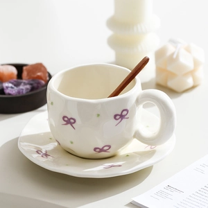 Detail of irregular white ceramic mug with purple bow patterns and a wooden spoon