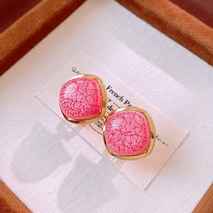 Macro shot of pink crackle texture stud earrings with elegant gold metal frames