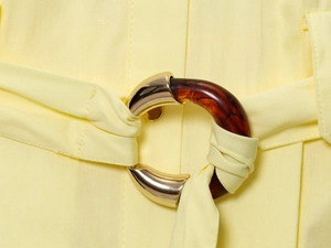 Detailed macro view of yellow poplin dress belt with resin and gold metal buckle