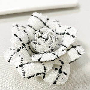 Close-up of white and black houndstooth pattern fabric camellia flower brooch texture