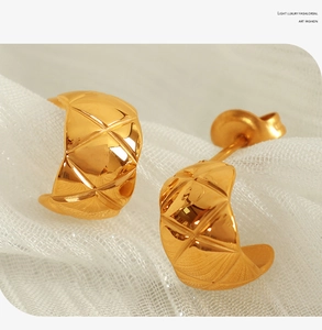 Macro view of gold-plated titanium C-shaped hoop earrings with quilted stripe pattern