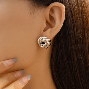 Close-up of a silver twisted knot earring on model showing elegant metallic details