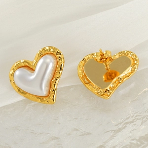 Detailed view of 18k gold heart earrings with white pearl inlay and hammered texture