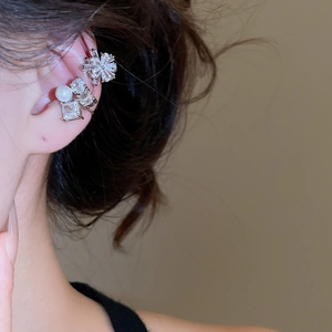 Detailed view of silver cuff earrings with zircons and pearls worn on a model's ear