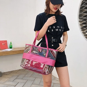 Clear PVC beach tote bag with pink trim and shoulder straps shown on a female model