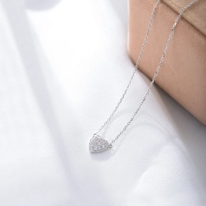 Close-up of S925 sterling silver heart pendant with shimmering pavé zircon on white fabric