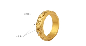Macro shot of 0.5cm gold vintage band with embossed sun moon motifs and zircon inlay