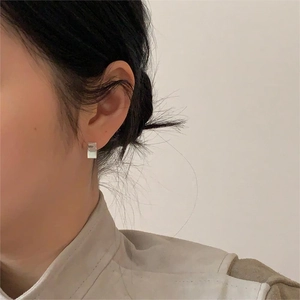 Close-up of square 925 silver stud earring with brushed metal finish on model's ear
