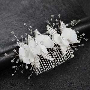 Detail of white fabric flowers and beaded pearls on a silver wedding hair comb bridal piece