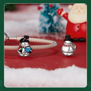Macro shot of silver snowman charm with colorful enamel on a mesh bracelet