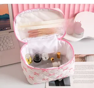 Detail showing high-capacity interior of white quilted cosmetic bag with pink bows