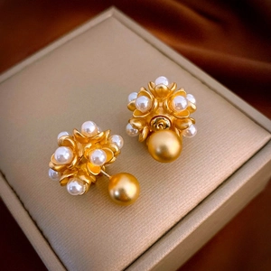 Vintage gold pearl flower stud earrings displayed on a champagne jewelry box surface