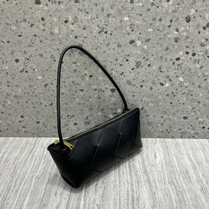 Detail of black woven leather shoulder bag showing intricate texture and golden zipper