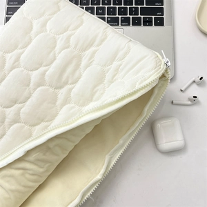 Detail view of cream quilted laptop sleeve with cloud pattern and soft protective lining