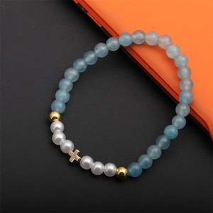 Détails du bracelet avec perles bleu clair, perles blanches et pendentif croix dorée