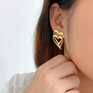 Nahaufnahme von Model mit goldenen 18K doppelten Herz-Ohrsteckern aus Edelstahl