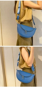 Detail of blue lychee leather crescent bag featuring silver zippers and wide fabric strap