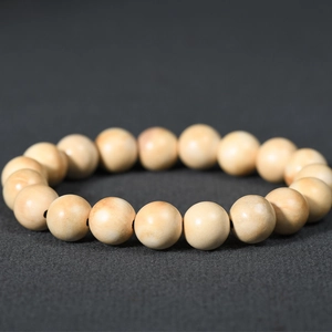 Natural light cream wood bead bracelet with 15 smooth beads on dark textured background