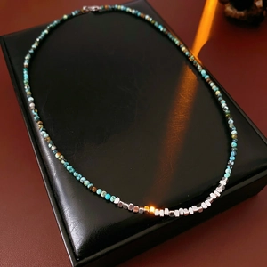 Vintage beaded necklace with turquoise stones and silver-tone cubes on a leather display