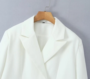 Detailed view of white long-sleeved blazer with classic lapels on a wooden hanger