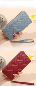Detail of long zip wallets in blue and red featuring heart embroidery and woven texture