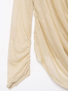 Close-up of beige knit fabric featuring Ruched side seams and detailed stitching textures