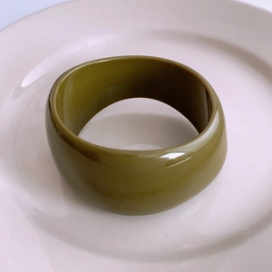 Gros plan sur le bracelet en acrylique vert olive avec finition brillante sur plat