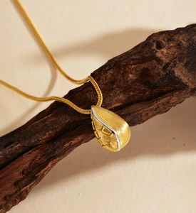 Detailed view of matte gold water drop pendant with natural texture on a snake chain