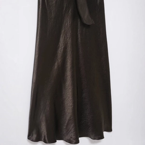 Dark brown satin dress with a smooth glossy texture and elegant draped hemline detail