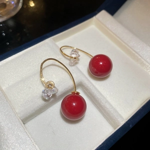 Macro detail of red resin beads and sparkling zircon stones on gold-plated drop earrings